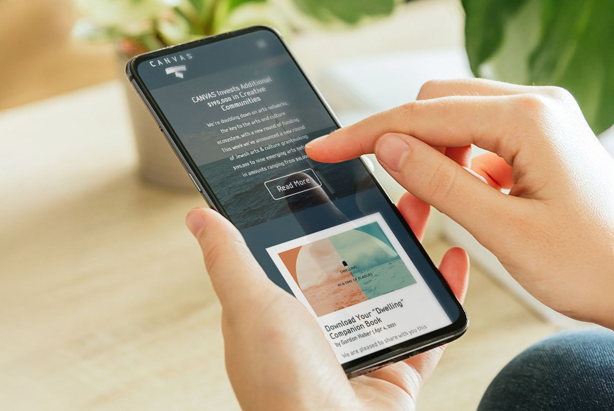 A hand holding a phone with CANVAS responsive Website Design